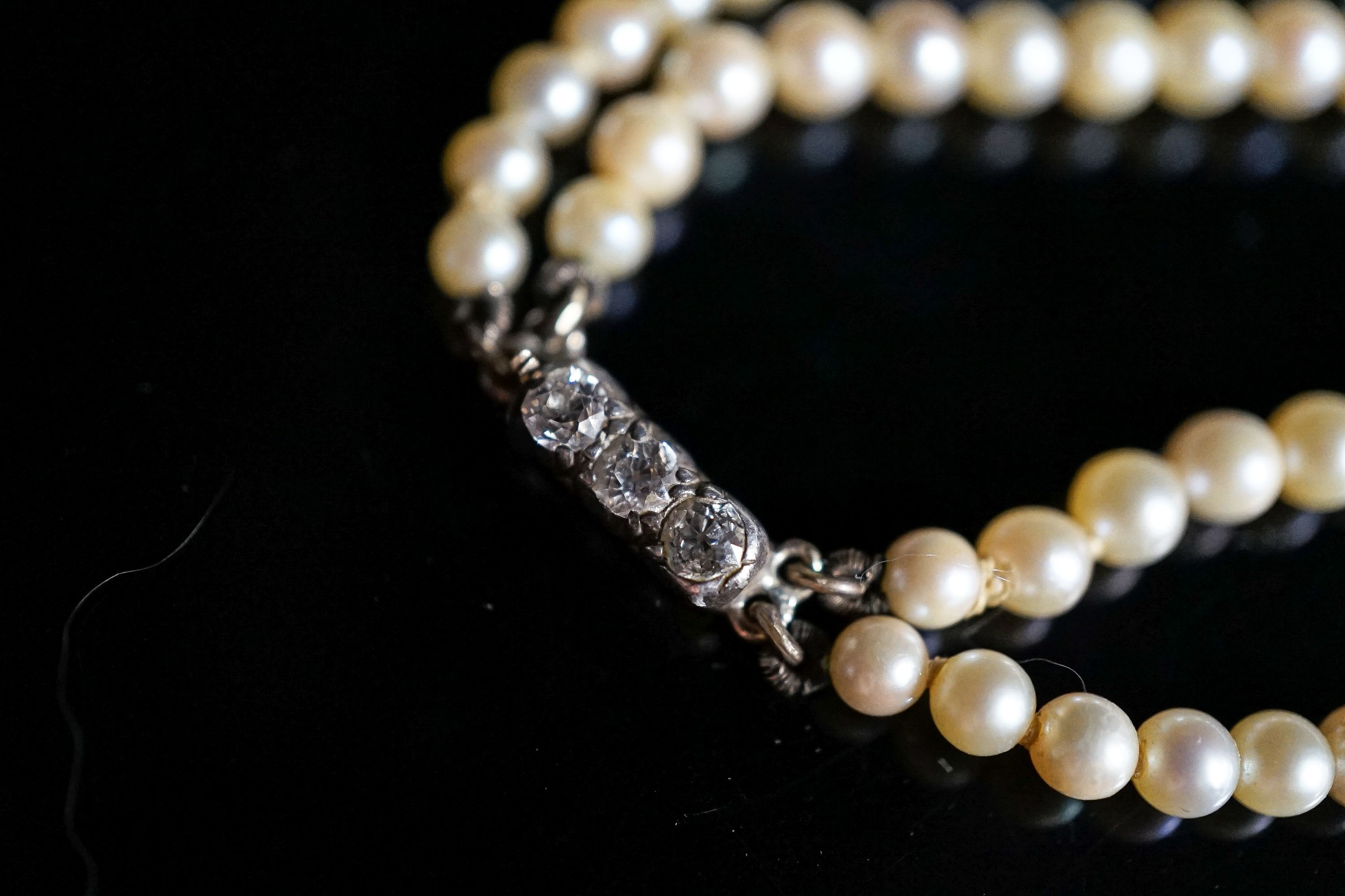 A double strand graduated cultured pearl choker necklace, with three stone diamond set clasp, 39cm.